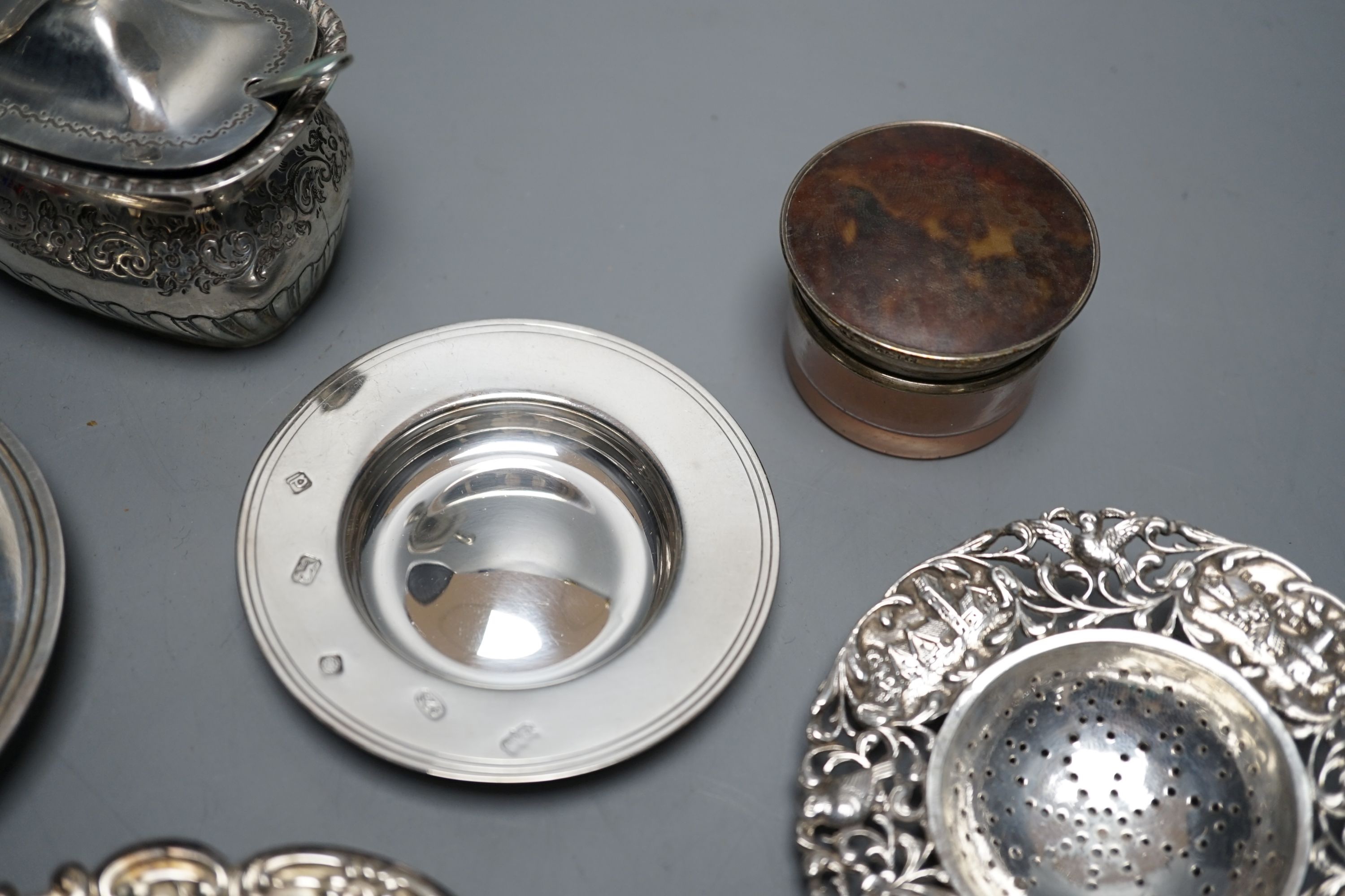 A late Victorian silver mustard, Sheffield, 1895, two small silver armada dishes, a silver bonbon dish, silver tea strainer(a.f.) and a silver mounted glass toilet jar.